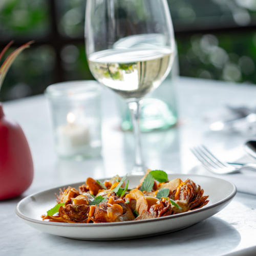 Fried artichokes on a plate with a glass of white wine