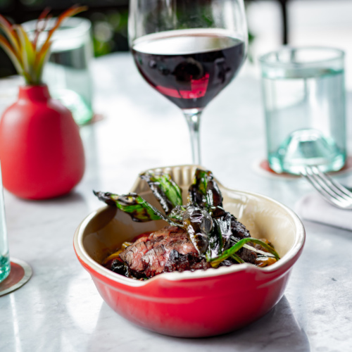 Seared steak dish and a glass of red wine