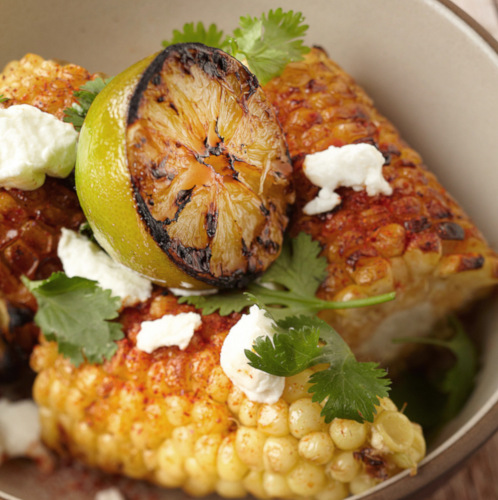 Spiced corn on a cob with lemon and cream, closeup